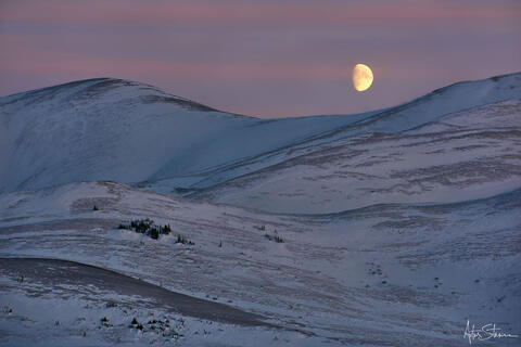 The moon rises over the mountains in Canadian Arctic.